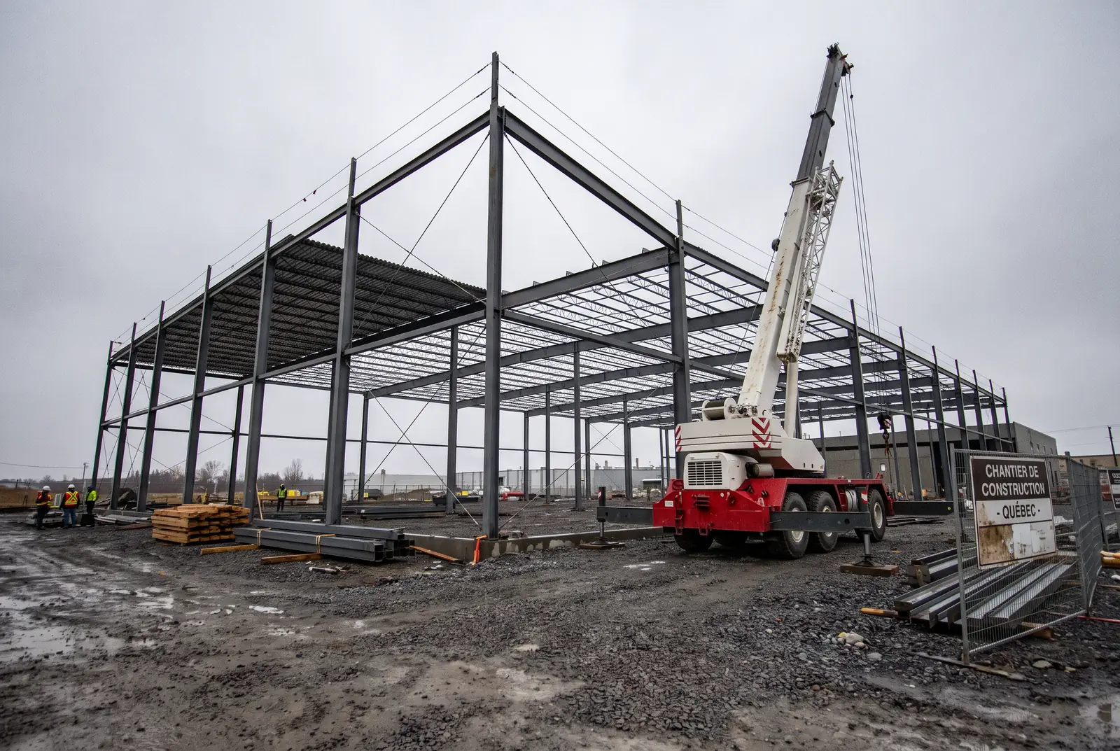 Ossature d'acier d'un bâtiment industriel en érection avec grue mobile sur un chantier du Québec